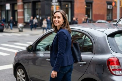 Femme confiante en blazer bleu près d'une voiture urbaine
