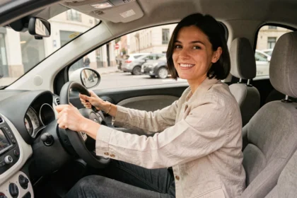 Jeune femme au volant d'une voiture sans permis en ville, vue de l'intérieur