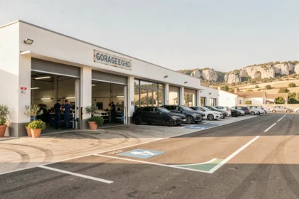 Vue extérieure d'un garage automobile dans le Gard avec mécaniciens et véhicules garés devant la façade