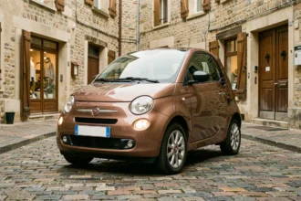 Voiture sans permis Fiat garée dans une rue pavée d'un village français, vue en trois quarts avant